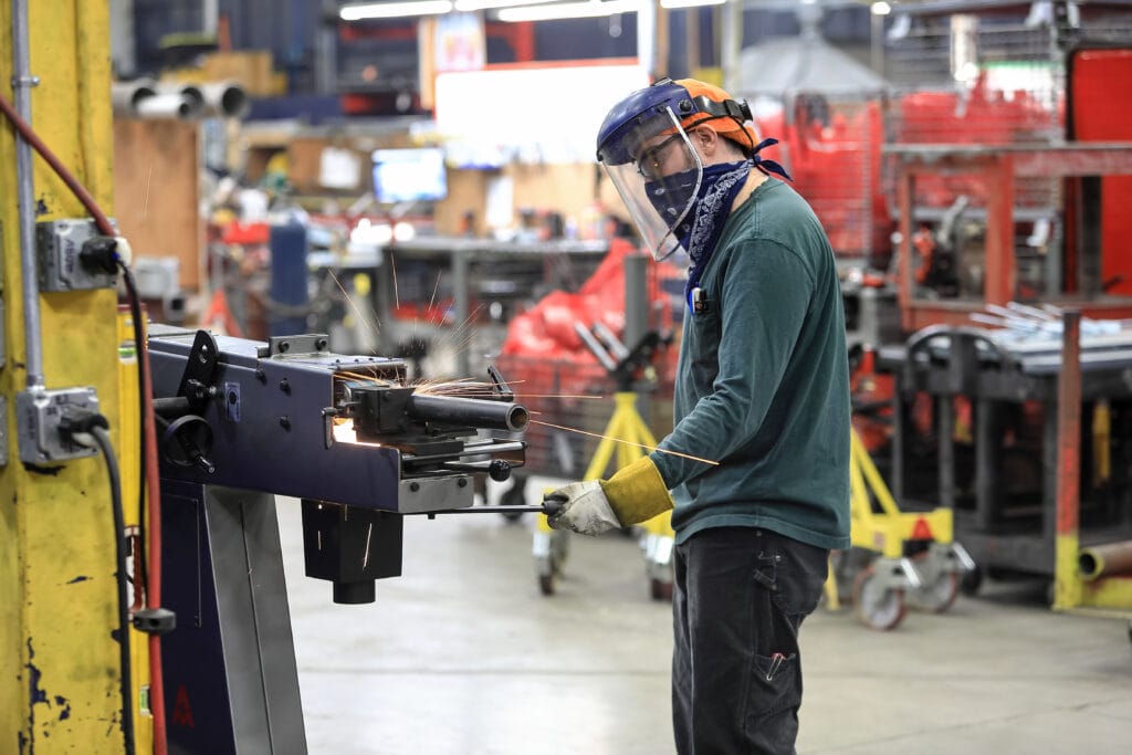 Fabrication shop employees cutting pipe