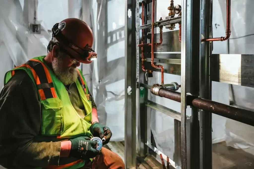 Auburn Mechanical employee in hardhat working on piping
